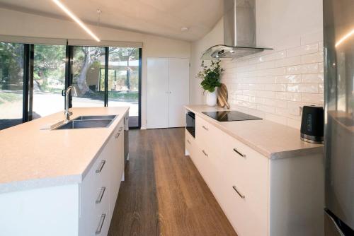a kitchen with white counter tops and wooden floors at Gumleaf Villa Hosted by Halls Gap Accommodation in Halls Gap