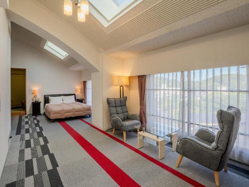 a bedroom with a bed and two chairs and a couch at Hotel Luna Park in Matsuyama