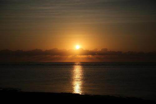 a sunset over the water with the sun setting at HERO VILLA ocean suite in Ishigaki Island