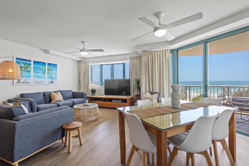 a living room with a blue couch and a table with chairs at Grand Palais Boolarong Beachside Apartments in Alexandra Headland