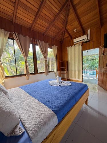 una camera da letto con un letto con una coperta blu e finestre di Hotel El Congo a Bahía Drake