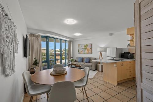 a kitchen and living room with a table and chairs at Grand Palais Boolarong Beachside Apartments in Alexandra Headland