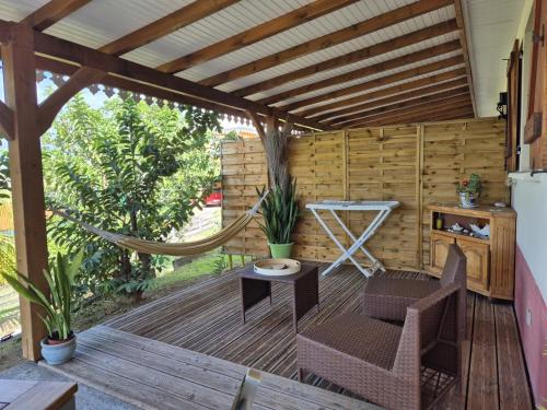 a patio with a hammock on a wooden deck at Ti Sucrier Jaune - Douceur caraïbe vue mer in Le Carbet