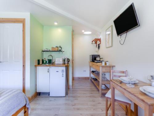 a room with a kitchen with a table and a television at Beinn Uidhe Studio Apartment - Uk49100 in Inchnadamph