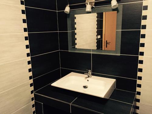 a black tiled bathroom with a sink and a mirror at Old Town Boutique Apartments in Liberec