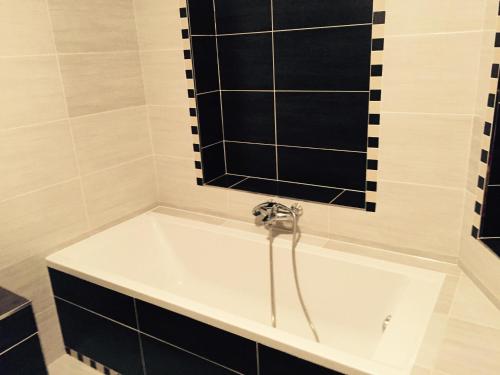 a bath tub in a bathroom with black and white tiles at Old Town Boutique Apartments in Liberec