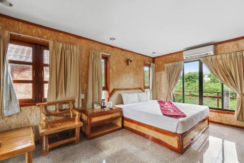 a bedroom with a bed and a desk and windows at Chanta Boutique Place in Ubon Ratchathani