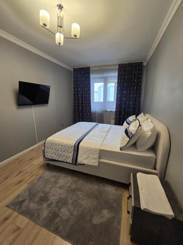 a bedroom with a large bed and a television at Алматушечка in Almaty