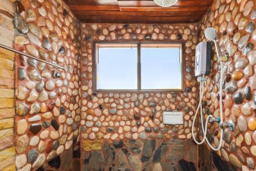 a bathroom with a stone wall and a window at Chanta Boutique Place in Ubon Ratchathani