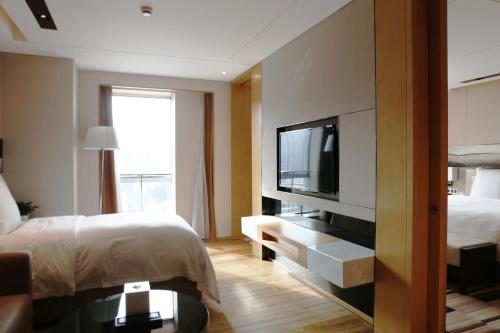a hotel room with a bed and a flat screen tv at Langham Place Xiamen in Xiamen