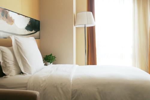 a white bed in a hotel room with a window at Langham Place Xiamen in Xiamen