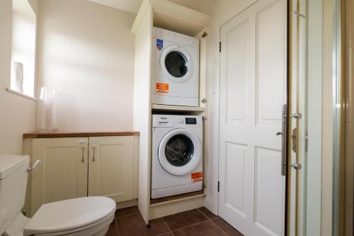 a bathroom with a toilet and a washer and dryer at Cozy Connemara Family Retreat in Derroogh