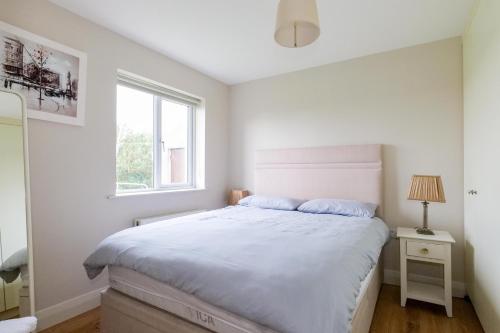 a bedroom with a white bed and a window at Cozy Connemara Family Retreat in Derroogh