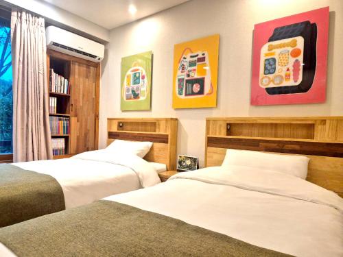 a bedroom with two beds and some pictures on the wall at Nami Island Hotel Jeonggwanru in Chuncheon