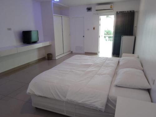 a large white bed in a room with a tv at Illusion Hostel & Club in Pattaya South