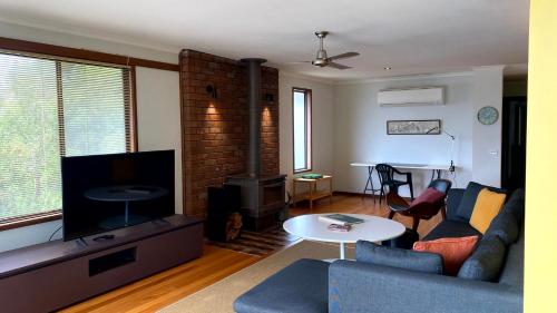 a living room with a couch and a tv at On The Hill at Metung - Quiet Retreat with Views in Metung