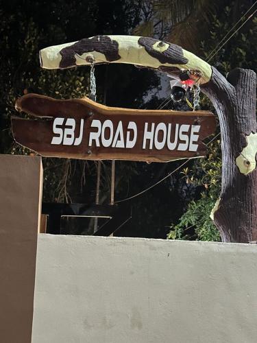 a sign for arl road house attached to a tree at SBJ Road House in Varkala
