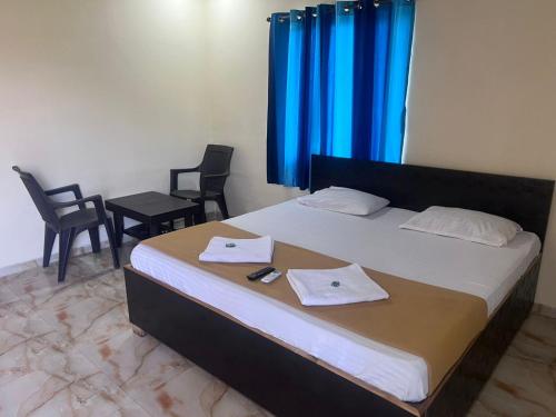 a bedroom with a bed with two chairs and blue curtains at Samadhan lodge in Vangani