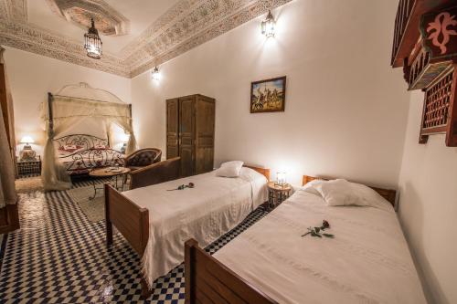 a hotel room with two beds and a chair at Riad Sara in Fès
