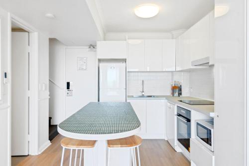 a white kitchen with a table in the middle at Alex Beach Front Nest in Alexandra Headland