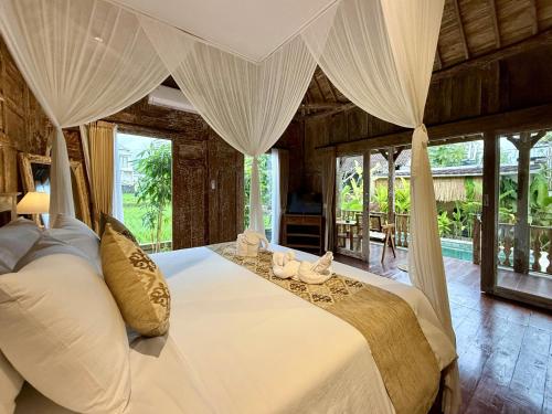 a bedroom with a large white bed with curtains at Sunshine dijoglo villa in Ubud