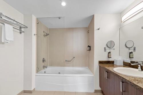 a white bathroom with a tub and a sink at Arya Hotel & Suites in Miami