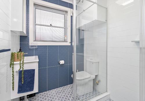 a bathroom with a toilet and a glass shower at Reddall Waterside Stay in Lake Illawarra