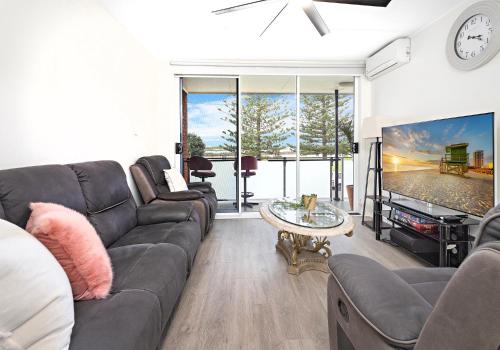 a living room with a couch and a tv at Reddall Waterside Stay in Lake Illawarra