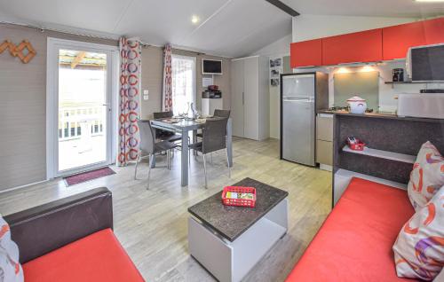 a living room with a red couch and a kitchen at Mobile-Home Proche Mer 400M in Grandcamp-Maisy
