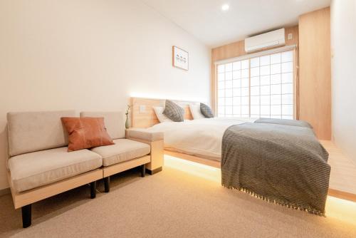 a bedroom with a couch and a bed and a window at b&黒門3号店 in Osaka