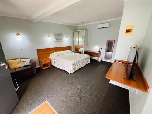 a hotel room with a bed and a television at Colonial Motor Lodge Scone in Scone