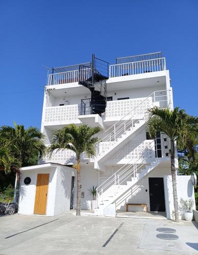 a white apartment building with stairs and palm trees at Stäy Hotel in Nago