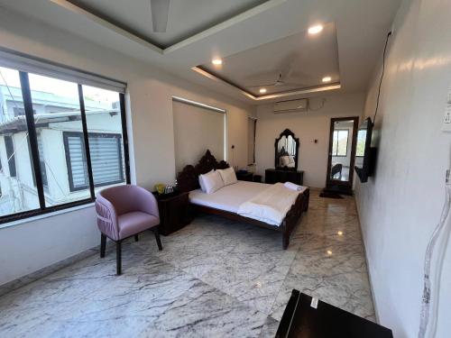 a bedroom with a bed and a chair and windows at Urban Nest in Nagpur