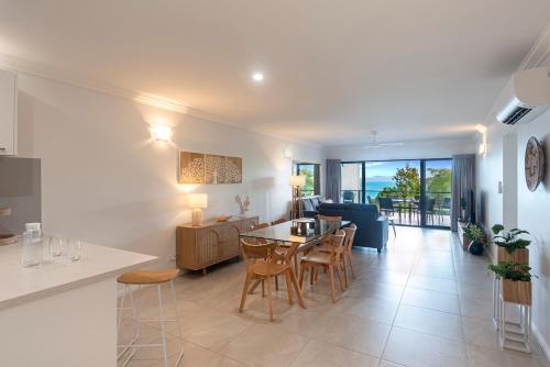 a kitchen and living room with a table and chairs at Compass Point on Hamilton Island by HIHA in Hamilton Island