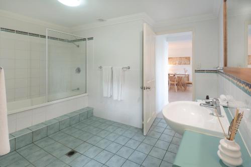 a white bathroom with a shower and a sink at Compass Point on Hamilton Island by HIHA in Hamilton Island