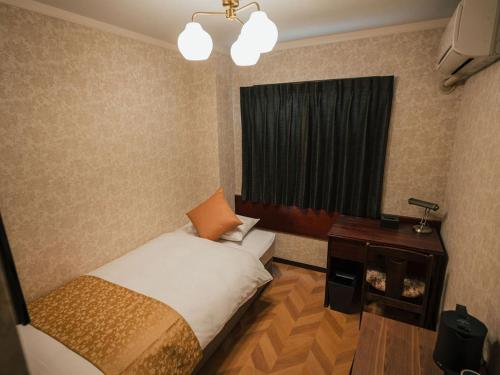 a bedroom with a bed and a desk and a window at KANSEI null 佐賀 in Saga