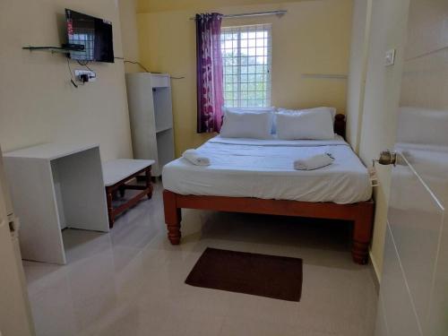 a small bedroom with a bed and a window at ISIRI Rooms in Mysore