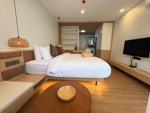 a bedroom with a large white bed and a table at Wing Samui Condo 102 in Nathon Bay