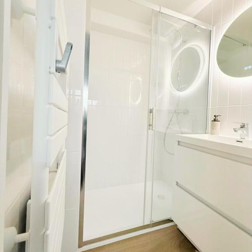 a white bathroom with a shower and a sink at Chalet Le Reposou in Laguiole