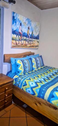 a bedroom with a bed with a painting on the wall at Coming Home in Centurion
