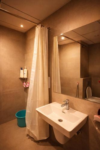 a bathroom with a sink and a shower curtain at Midnight Atelier in Greater Noida