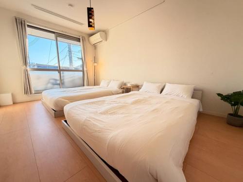 two beds in a room with a window at Franmare in Okayama
