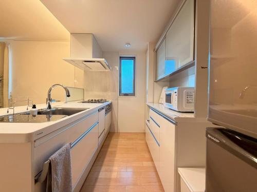 a white kitchen with a sink and a microwave at Franmare in Okayama