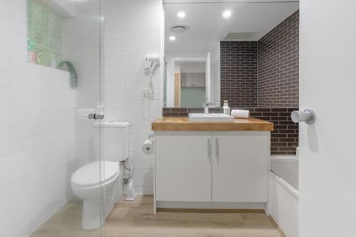 a white bathroom with a toilet and a sink at Bay View Style in Lorne