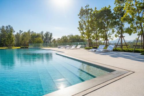 an infinity pool with lounge chairs next to a swimming pool at Laguna Beachside residences apartamens, walking distance to the sea in Bang Tao Beach