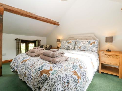 a bedroom with a bed with a comforter and towels on it at Redstart Cottage in Leominster
