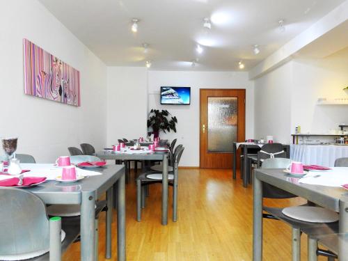 a dining room with tables and chairs with pink napkins at Hotel zum Brunnen in Friedberg