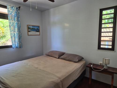 una camera da letto con un letto, un tavolo e una finestra di Te Fare Ninamu a Taputapuapea
