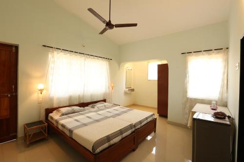 a bedroom with a bed and a ceiling fan at Sea Pearl Guesthouse in Candolim
