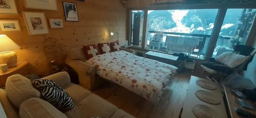 a living room with a bed and a large window at Mountain Studio in La Tzoumaz